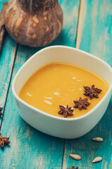 Pumpkin and carrot soup with cream and parsley on blue  wooden background.