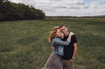 couple of young men and women are hugging closely in field against the background of haystacks. autumn landscape of nature. local travel. family relationships. selective focus