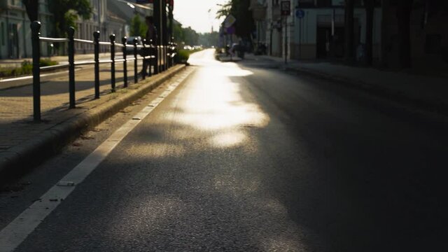 Reflecting sunlight from the road while a cyclist riding a bike on the sidewalk - slow-motion