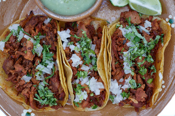 Tacos al pastor, tradicional comida mexicana, con cebolla, cilantro, piña, salsa roja o guacamole.