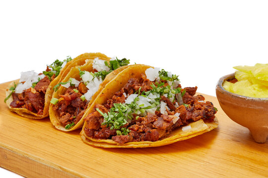 Tacos al pastor, tradicional comida mexicana, con cebolla, cilantro, pi&ntilde;a, salsa roja o guacamole.