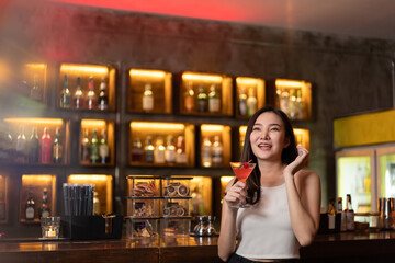 Nightlife concept a pretty girl with long hair wearing white and jeans holding a pink drink appreciating the musics alone in the bar
