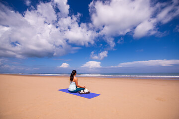 people and leisure concept- back view of woman meditating and drinking tea on the tropical beach with blue sky vackground