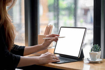 Close-up of a businesswoman hand holding a stylus pen ready to use a tablet blank white screen at...