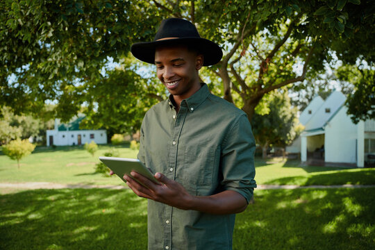 mixed race male farmer standing outdoors typing on digital tablet 