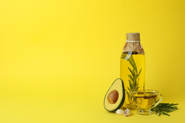 Bottle and sauce boat of oil and ingredients on yellow background