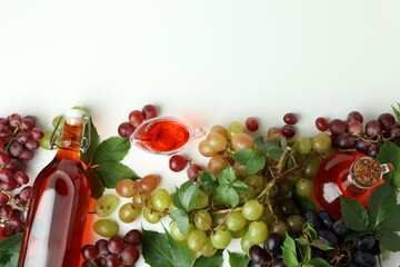 Bottles of vinegar and grape on white background, top view