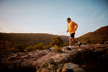 Fitness male running through rocky mountain path