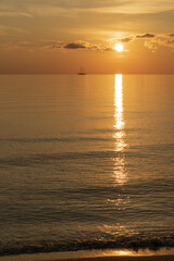 Alba sul mare, con riflesso del sole che sorge sull'acqua e cielo nuvoloso