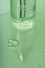 Cosmetic transparent bottle dropper container on a green background with gel liquid.