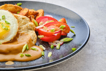 Closeup view of chopped pork sirloin with fried potato wedges, egg, tomato and radish