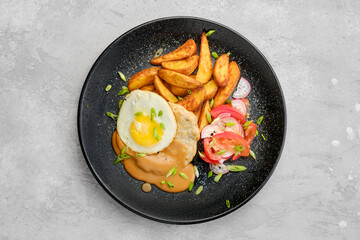 Top view of chopped pork sirloin with fried potato wedges, egg, tomato and radish
