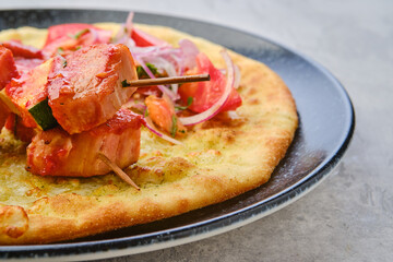 Closeup view of shashlik served on tortilla with tomato and onion