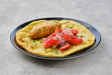 Kebab served on tortilla with tomato and onion