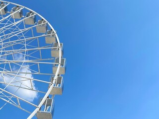 Ferris wheel in the amusement park against blue sky at sunny summer day.