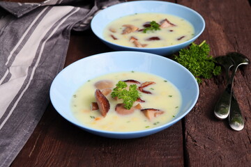 Creamy soup with porcini mushroom and herbs on wooden table