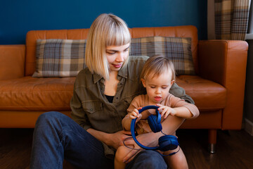 Young woman with headphones and baby at home.