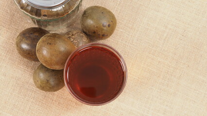 Monk fruit or Luo Han Guo. Dried fruits for healthy sweetener drink. Natural herbal remedy and glass bottle background. Monk fruit drink for who concern health and sugar substitute. 