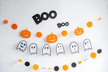 Festive decor on the white wall garland paper in the form of a pumpkin, ghost. Halloween holiday decor.