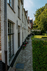 Fototapeta na wymiar Street view with flower pots in the shadows, old center of Bruges, Belgium