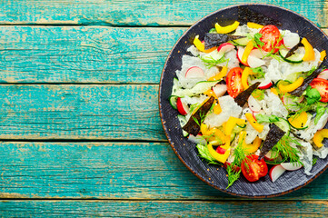 Vegetable salad decorated with rice paper on wooden table