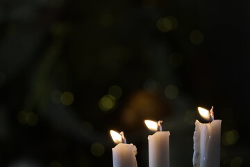 Candle fire close up on blurred christmas tree light background