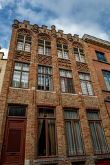 So many windows on that brick house! Street view of old Bruges, Belgium, cloudy summer day