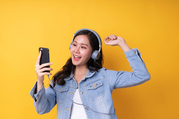 Asian women are listening to music and dancing to the beat through a headset connected to a smartphone. Good looking girls are happy and enjoying music on the phone. relax and rest time concept