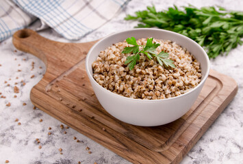 Freshly cooked buckwheat porridge in a plate on a gray background.