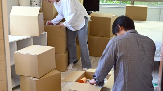 段ボールから引越しの荷解きをする男女