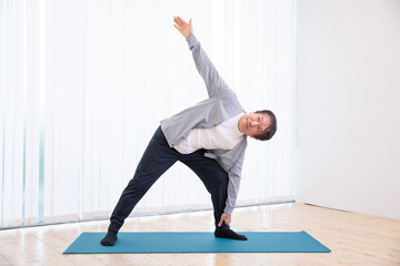 Fototapeta premium 部屋でヨガをする中高年男性（三角のポーズ） 