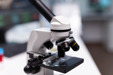 Close up of microscope in microbiology laboratory at science clinic. Scientific instrument with magnifying glass lens and transparent tray for liquid examination in research cabinet
