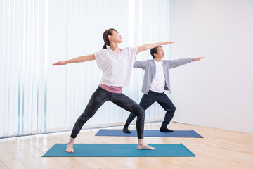 ヨガ・運動をする中高年の男女（戦士のポーズ）
