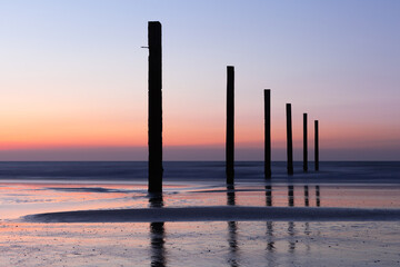 Pile heads at the beach of Lombardsijde near Middelkerke, Belgium at sunset.