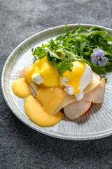 Sandwich with ham, cheese and herbs. Hearty, nutritious breakfast. Ready menu for the restaurant. Neutral gray blue textured background