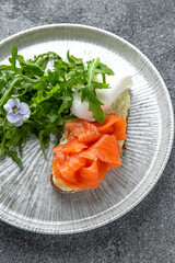 Bruschetta with salmon, poached egg and cheese. Ready menu for the restaurant. Neutral gray blue textured background