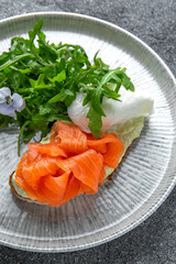 Bruschetta with salmon, poached egg and cheese. Ready menu for the restaurant. Neutral gray blue textured background