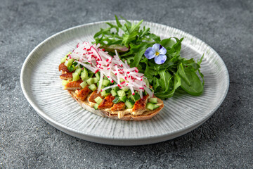 Bruschetta with smoked eel, cucumber and radish. Ready menu for the restaurant. Neutral gray blue textured background