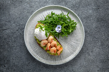 Bruschetta with guacamole and shrimp. Hearty, nutritious breakfast. Ready menu for the restaurant. Neutral gray blue textured background