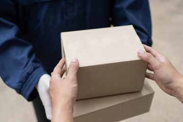 Parcel delivery concept the postman in white rubber gloves and light weight dark blue coat handing...