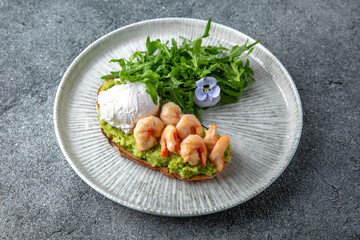 Bruschetta with guacamole and shrimp. Hearty, nutritious breakfast. Ready menu for the restaurant. Neutral gray blue textured background