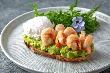 Bruschetta with guacamole and shrimp. Hearty, nutritious breakfast. Ready menu for the restaurant. Neutral gray blue textured background
