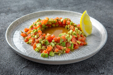 Salmon tartar with avocado with citrus sauce. Ready menu for the restaurant. Neutral gray blue textured background