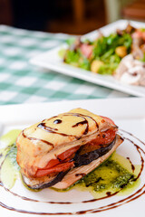 Rosemary chicken with oven-roasted ratatouille served on a white square plate over table with green plaid tablecloth.