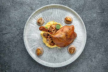 Duck confit with mashed potatoes and fried mushrooms. Ready menu for the restaurant. Neutral gray blue textured background