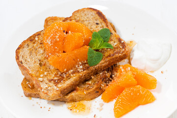 sweet french toast with jam and tangerines on the plate, closeup