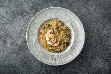 Risotto with wild mushrooms and champignons. Ready menu for the restaurant. Neutral gray blue textured background