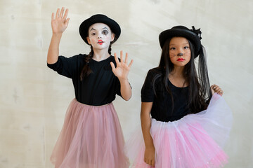 Two cute girls with halloween makeup performing pantomime in front of camera - obrazy, fototapety, plakaty