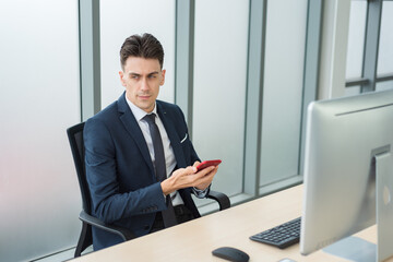 Handsome smart business man in suit outfit using smartphone to communicate with customer with serious emotion in modern office room