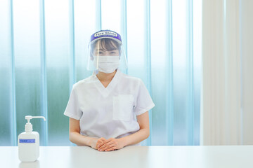 マスクとフェイスシールドをする白衣姿の女性
